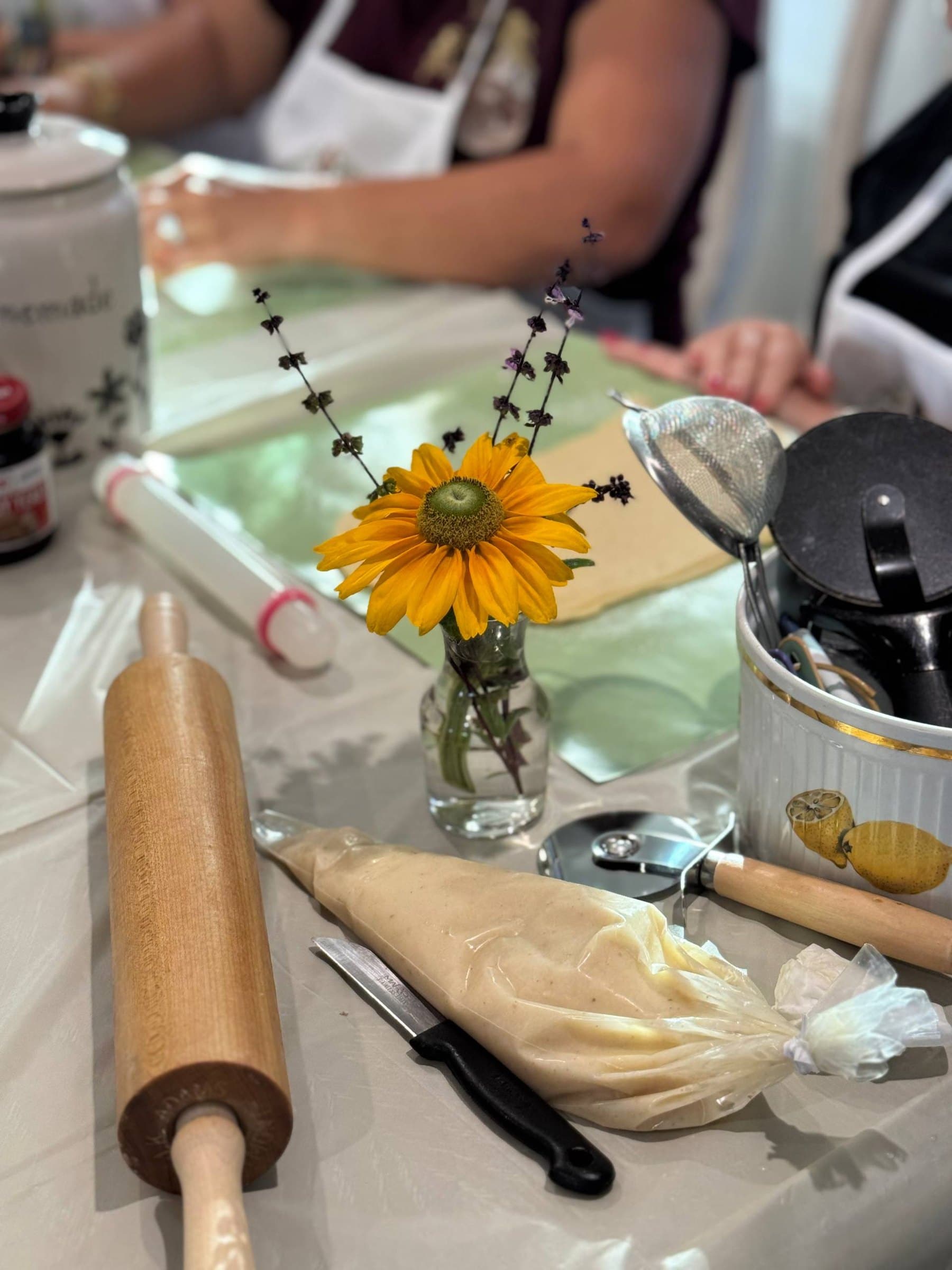A workshop table with a rolling pin, piping bag and a sunflower in a jar