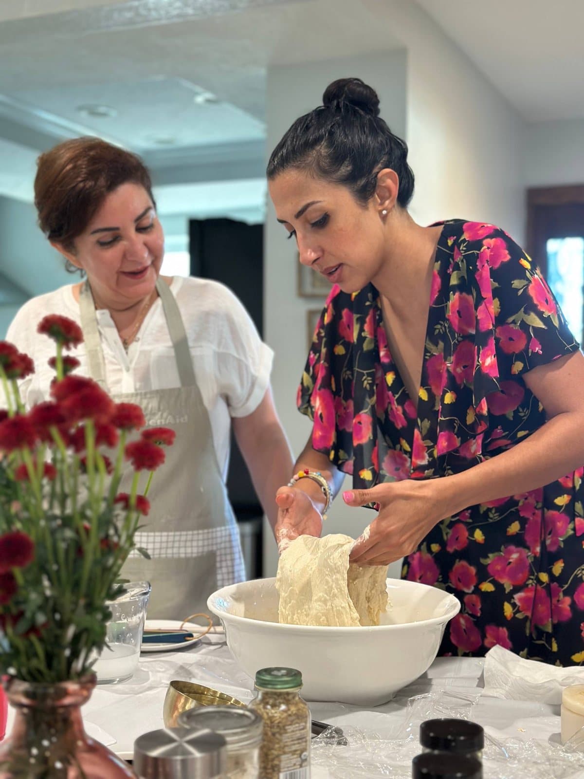 A guest lifting wet barbari dough out of the bowl at the workshop table