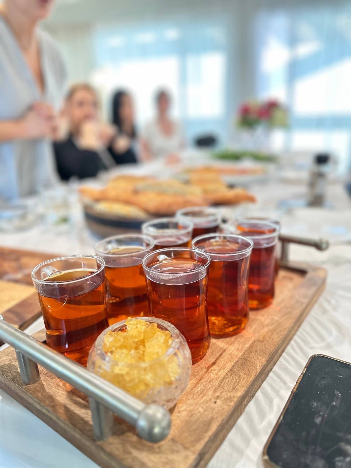 A tray of Persian tea in estekan glasses with a bowl of rock sugar, mid-workshop