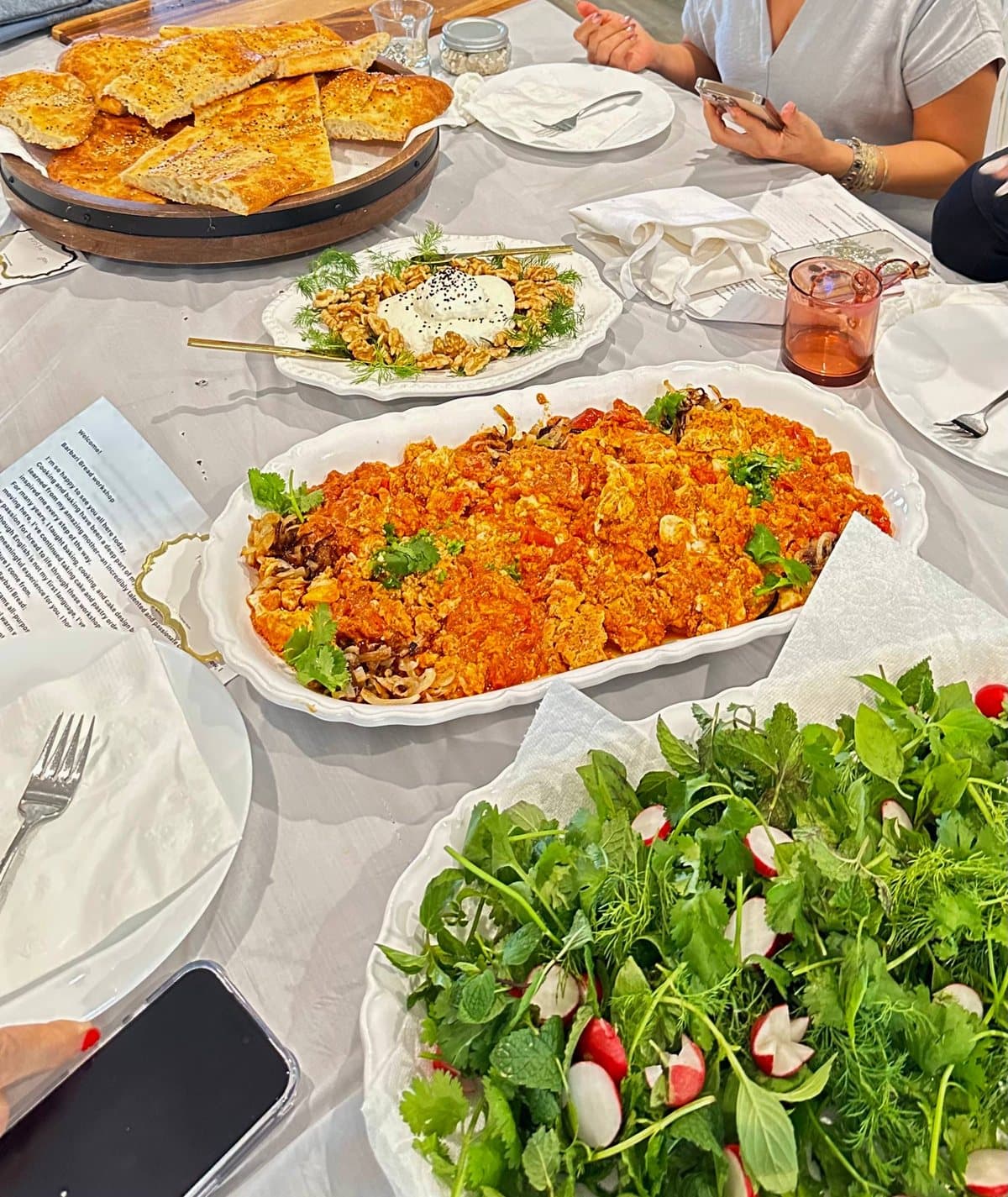 The table mid-workshop: barbari, walnuts and yoghurt, a hot platter and a pile of fresh herbs