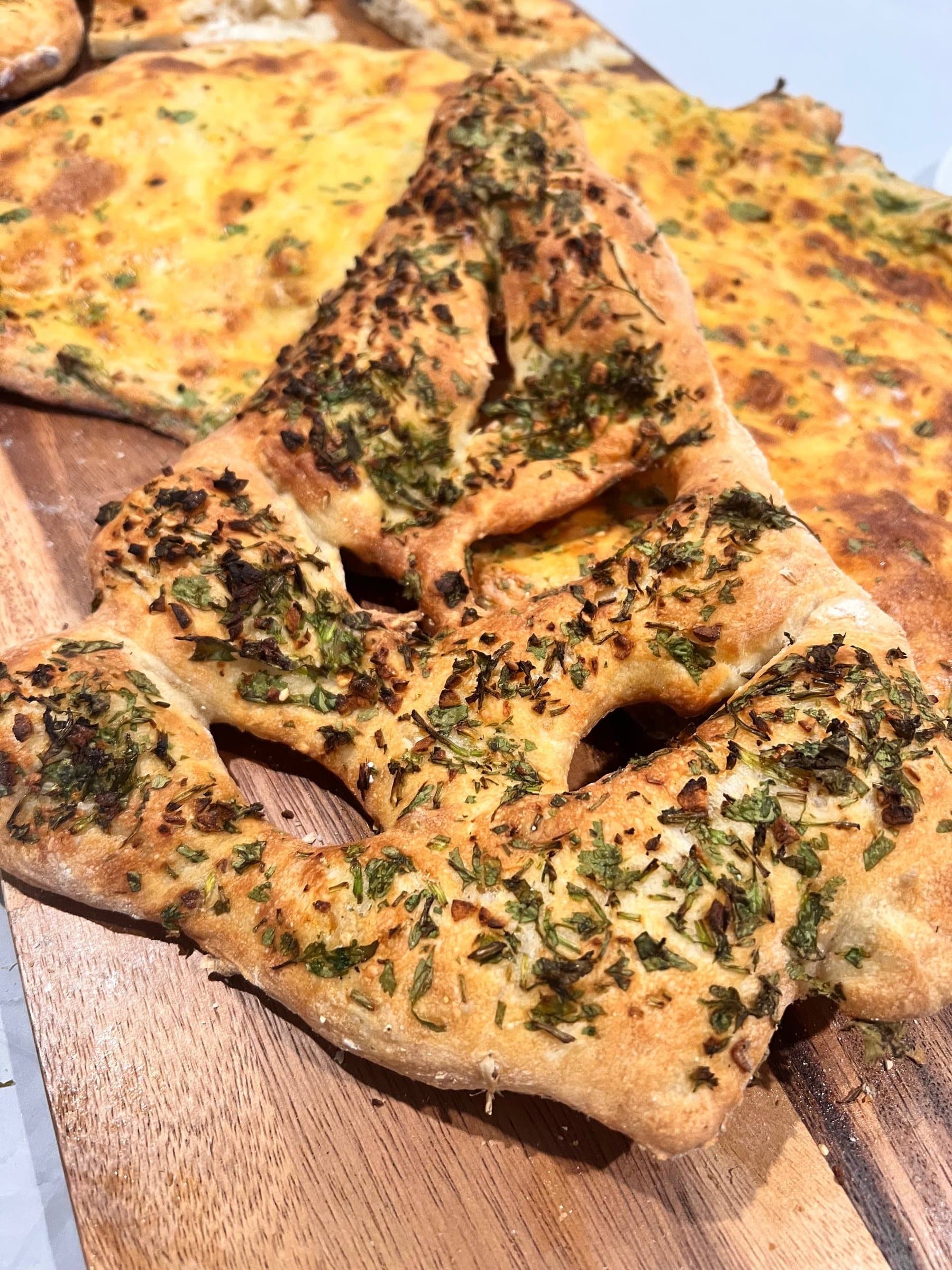 Herb-topped barbari, slashed and baked golden, cooling on a wooden board