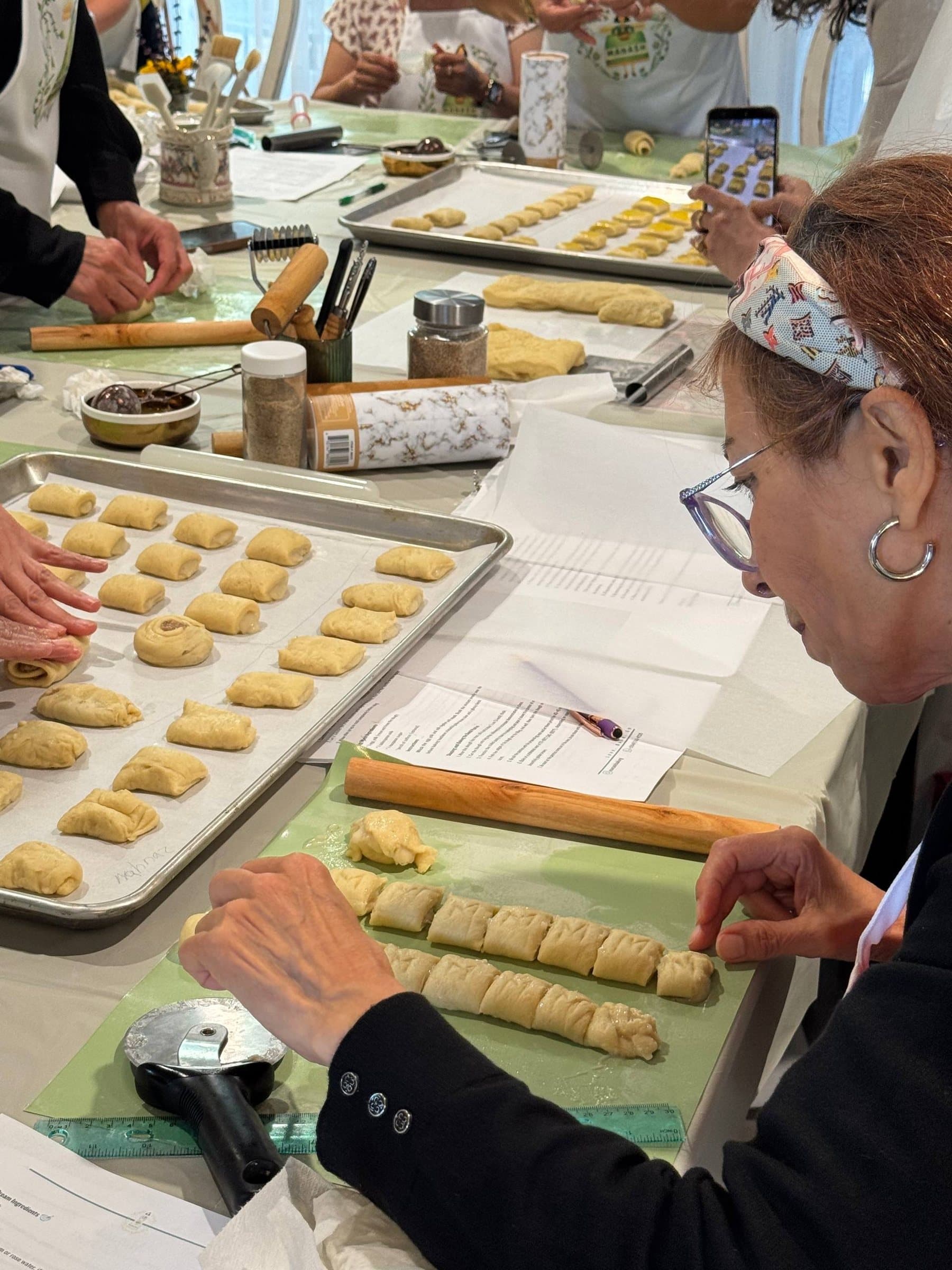 Guests rolling and cutting Danish pastry, with trays of shaped pieces alongside
